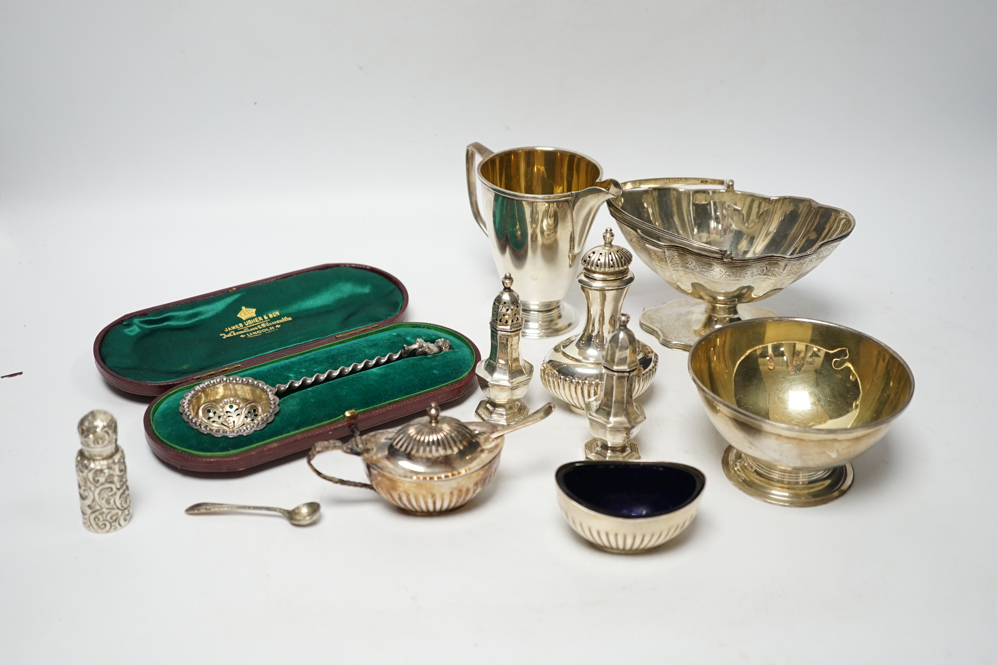 A group of small silver including Edwardian silver oval sugar basket, a modern silver cream jug and sugar bowl, five assorted condiments, a silver sifter spoon and a late Victorian scent bottle, 56mm.